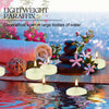 A set of floating candles made from lightweight paraffin wax resting on water with pink flowers and smooth stones.