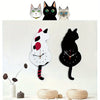 A whimsical black cat pendulum wall clock featuring a moving tail, displayed above several stylized cat figures.