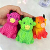 Three squishy toys shaped like Highland cows in pink, green, and orange colors held in a hand.