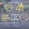 A collection of gold and rose gold acrylic cake toppers featuring birthday messages like Happy Birthday