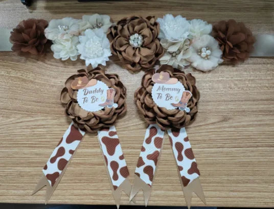 A set of floral maternity sashes and corsage pins featuring brown and cream flowers and brown ribbon with white spots.