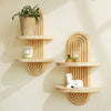 A set of wooden arc wall shelves featuring a rustic floating design, holding potted plants and candles.