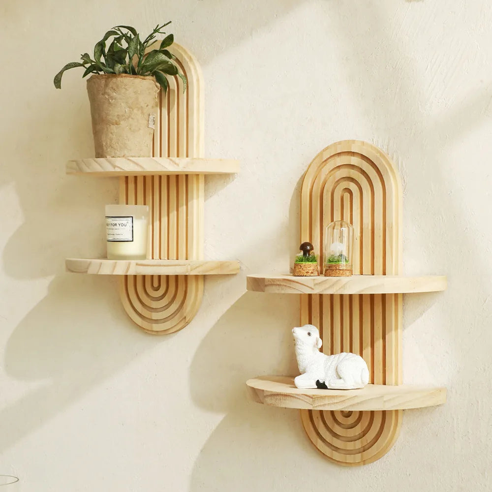 A set of wooden arc wall shelves featuring a rustic floating design, holding potted plants and candles.