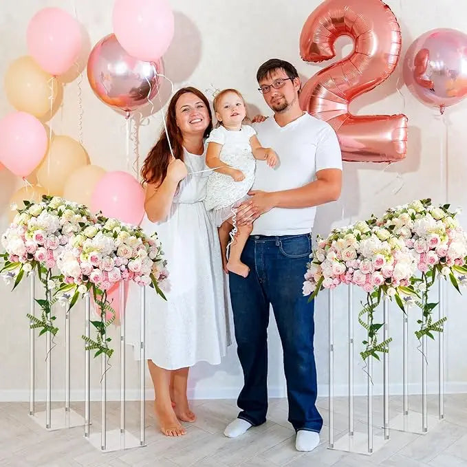 Un couple se tient devant une toile de fond de ballons roses avec des arrangements floraux blancs.
