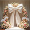 Giant satin bow with long tulle drape used as event decor featuring pink and cream floral arrangements