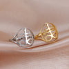 Silver and gold signet rings featuring a leviathan cross design displayed on a soft pink fabric.