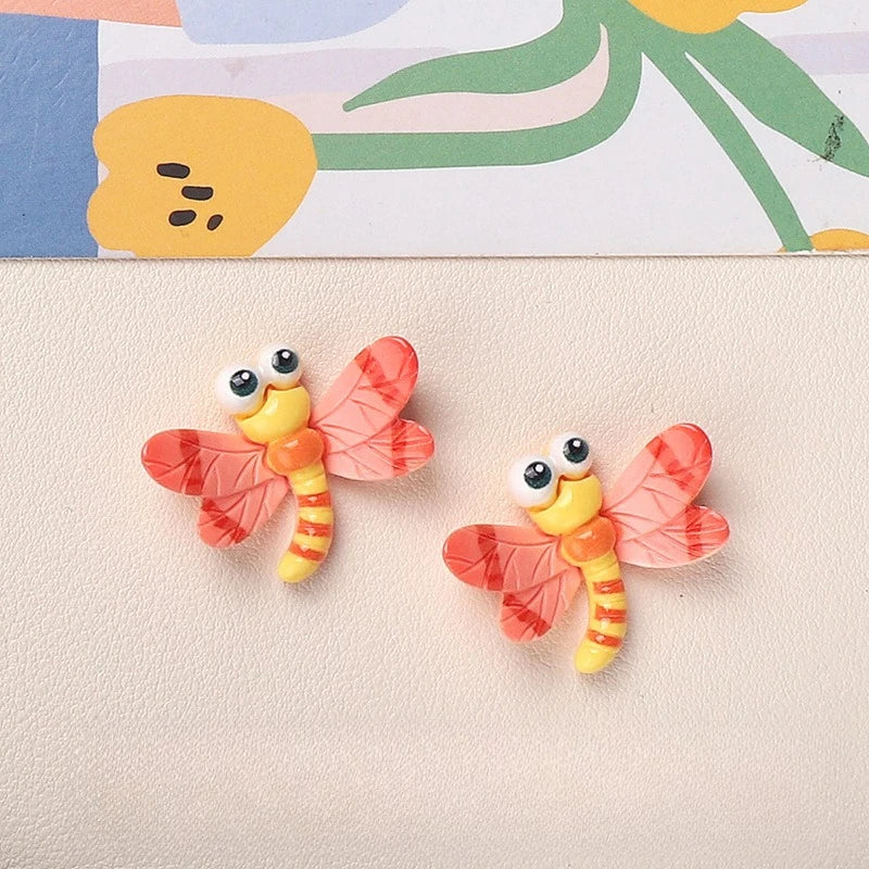 Two pink and orange resin insect magnets shaped like butterflies with yellow bodies