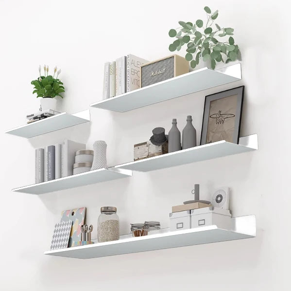 A white floating wall shelf system displaying various kitchen and storage items like jars, books, and greenery.