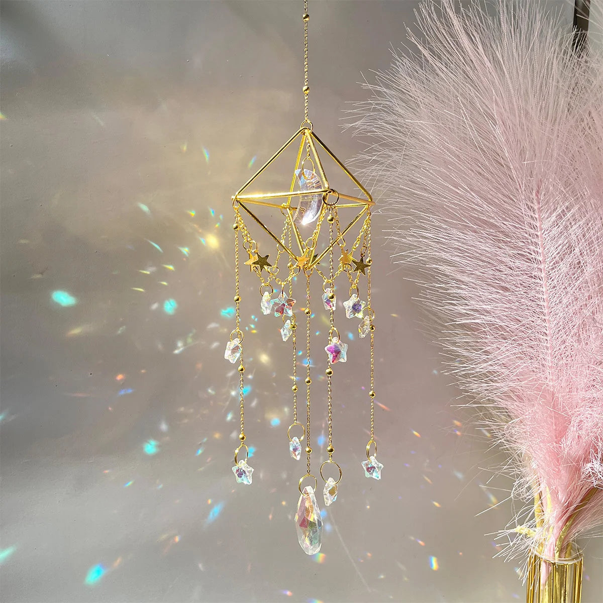 A golden crystal hanging suncatcher decoration with dangling clear and purple crystals against a soft, light background.