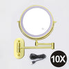 A round, illuminated magnifying makeup mirror with a gold frame and USB charging cable.