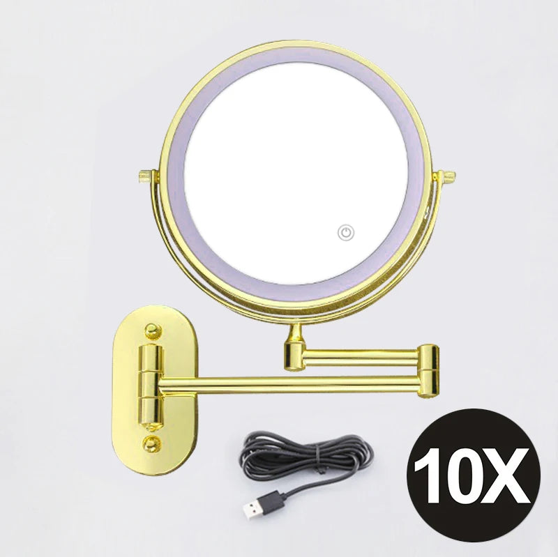 A round, illuminated magnifying makeup mirror with a gold frame and USB charging cable.