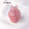 A pink rose quartz crystal heart carving decoration on a white background.