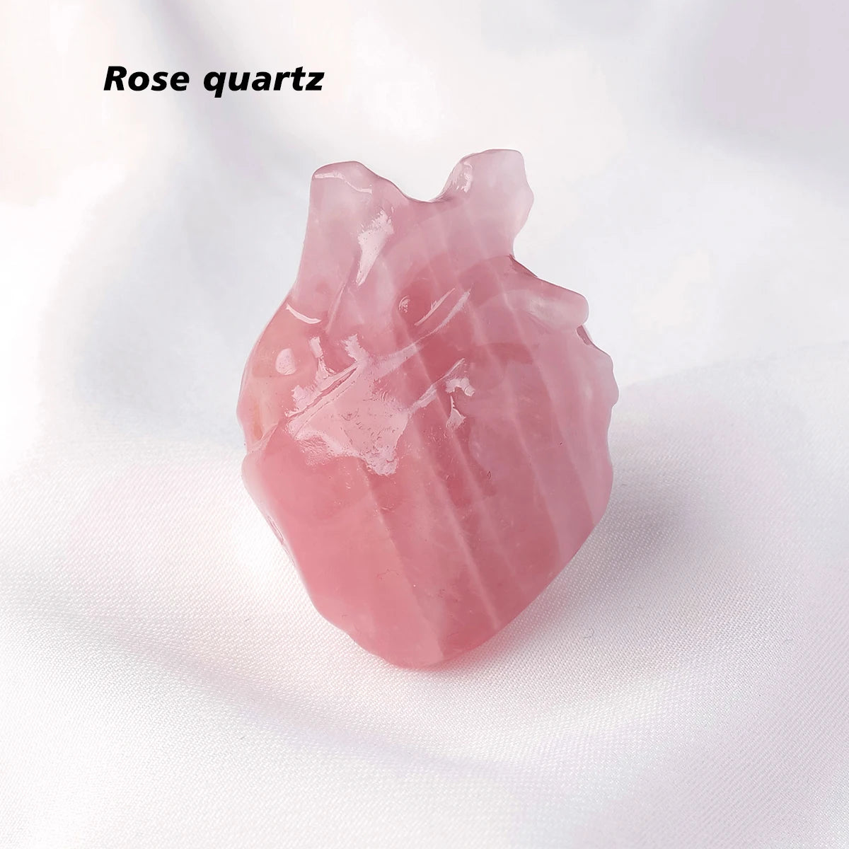 A pink rose quartz crystal heart carving decoration on a white background.
