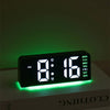 Reloj de alarma digital LED mostrando 8:16 con brillo verde sobre una superficie blanca.