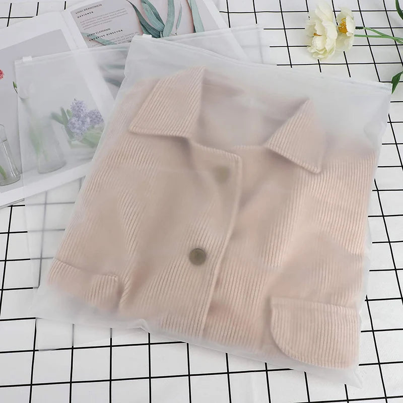 A beige knitted shirt is visible inside a clear plastic storage bag on a black grid surface.