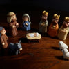 A set of nativity scene figurines depicting Mary, Joseph, and baby Jesus, displayed on a wooden surface.