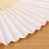 A fan made of light-colored bamboo slats, folded and displayed on a wooden surface.