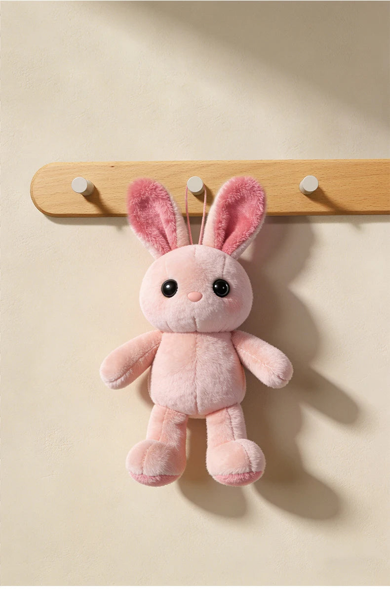 A pink fluffy rabbit hanging from a wooden wall hook rack.