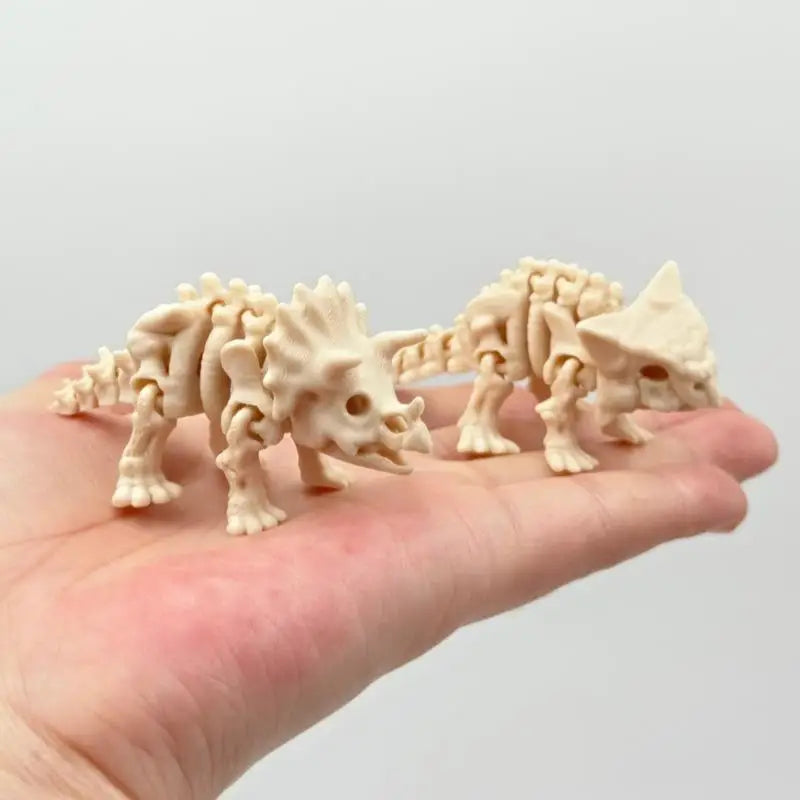 A light beige 3D printed dinosaur skeleton model is held in a person's hand.