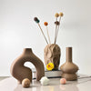 A set of three geometric ceramic vases in earthy brown tones displayed on a white surface.