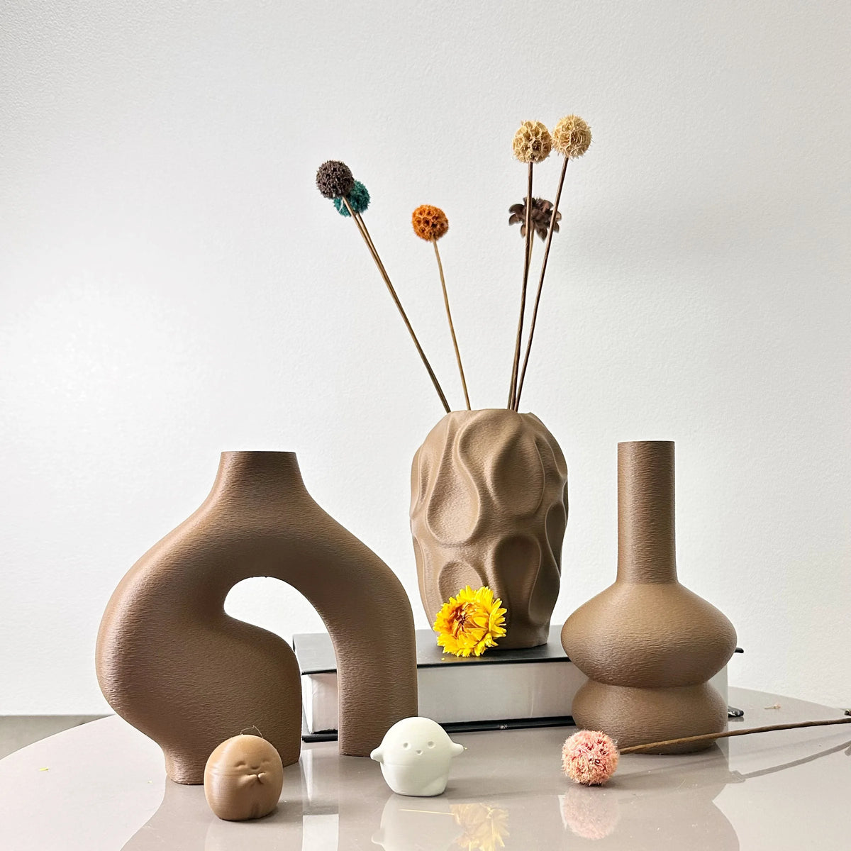 A set of three geometric ceramic vases in earthy brown tones displayed on a white surface.
