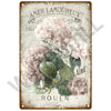 Vintage metal sign featuring text and floral illustrations with a muted pink and green color palette.