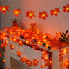 Orange maple leaf LED string lights decorating a white fireplace mantel for seasonal display