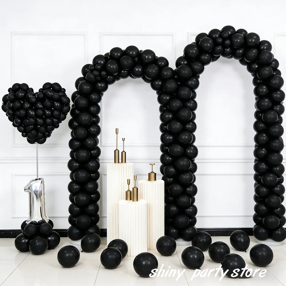 A black balloon archway decorated with black latex balloons and white candles.