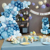 Una gran decoración de columna de globos azules y blancos con varios tonos de globos azules sobre una mesa.