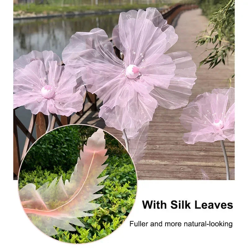 A set of three large pink sheer fabric flowers with silk leaves used as wedding decoration