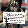 A wooden hanging sign with kitchen rules written on it is tied to a tree trunk.