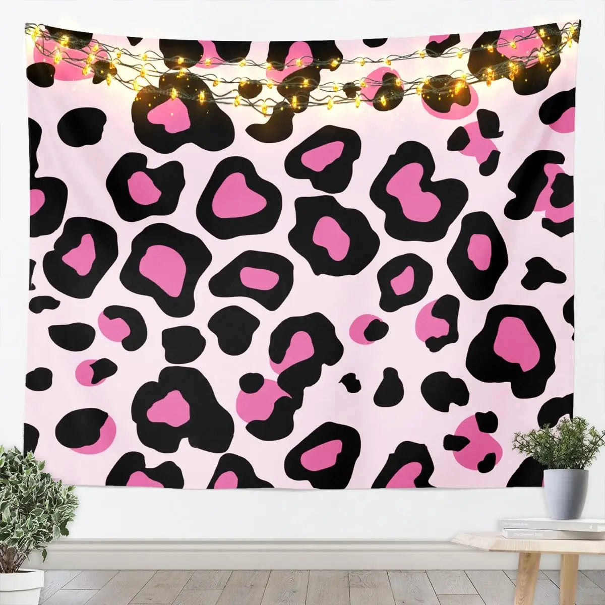 Pink leopard print tapestry wall hanging with warm string lights displayed on a white wall.