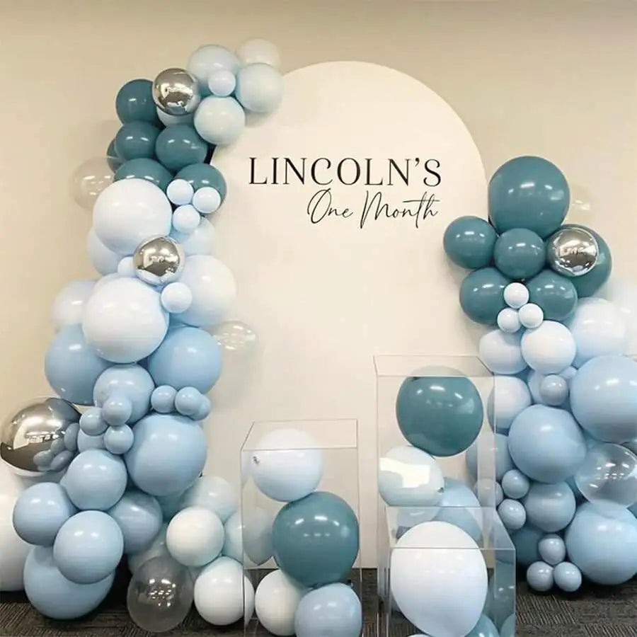 A cluster of dusty blue and light blue latex balloons arranged in a decorative arch against a white background.