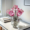 A glass vase filled with pink crystal rose-shaped decorative flowers on a white table.