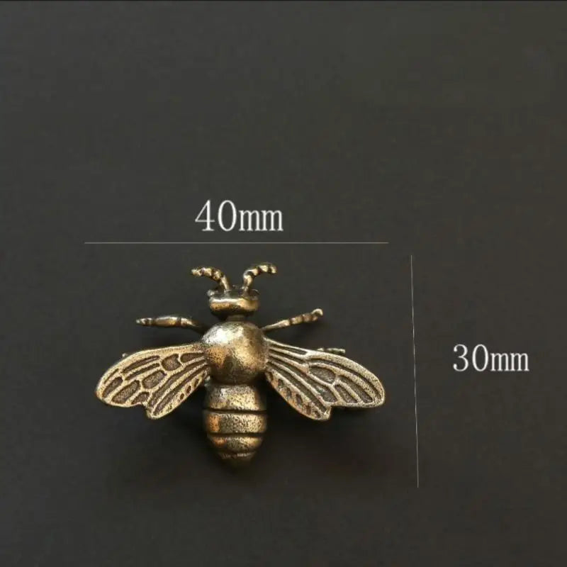 Figurine de guêpe en laiton vintage avec ailes et corps, présentée sur fond sombre.