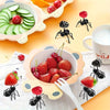 A collection of reusable ant-shaped plastic toothpicks and fruit forks used for party snacks, featuring strawberries, cherrie