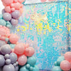 A shimmering pink and blue sequin wall backdrop for a party decoration featuring round balloons.