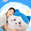 A soft white and blue Usagi Chiikawa plush doll is being cuddled by a woman in a light striped shirt.