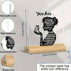 A clear acrylic desk decor featuring a silhouette of a woman with positive affirmations written in black text on a wooden bas