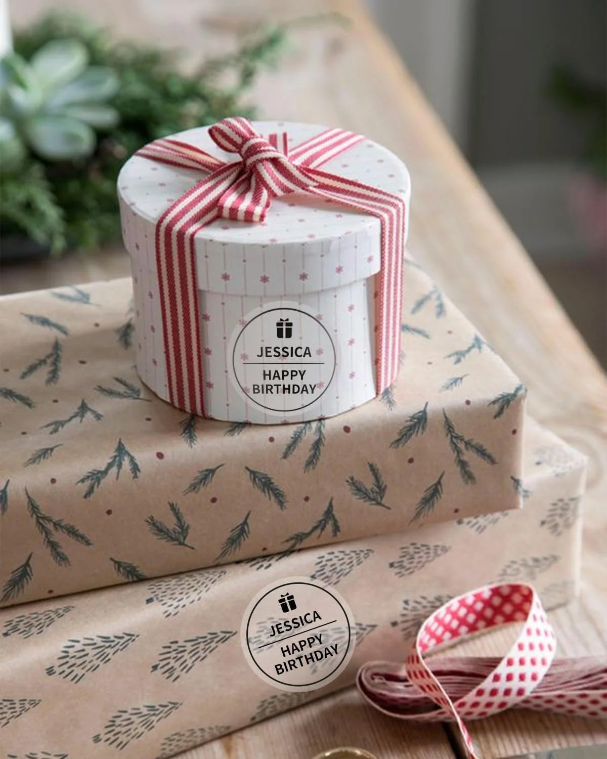 A gift box wrapped in kraft paper with a red and white striped ribbon, sitting on a larger piece of patterned paper.