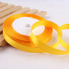 Roll of gold yellow satin ribbon on a wooden surface for crafts and gift wrapping