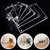 A stack of clear acrylic magnetic photo frames and a small wooden frame with photos.
