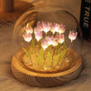 A clear glass globe containing a display of pink LED tulips on a wooden base.