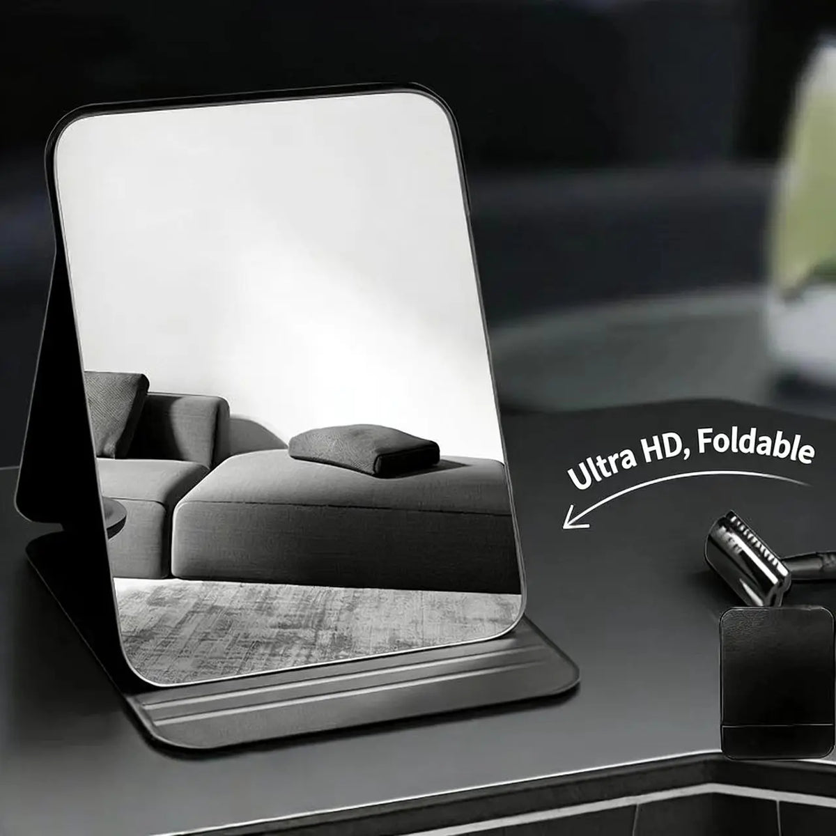 A foldable vanity mirror with an adjustable stand is shown on a dark surface, displaying a reflection.