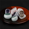 A collection of tumbled natural crystals including clear quartz, rose quartz, and amethyst on an orange dish.