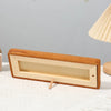 A wooden photo frame display stand with a rectangular opening and a natural wood finish is shown on a white surface.