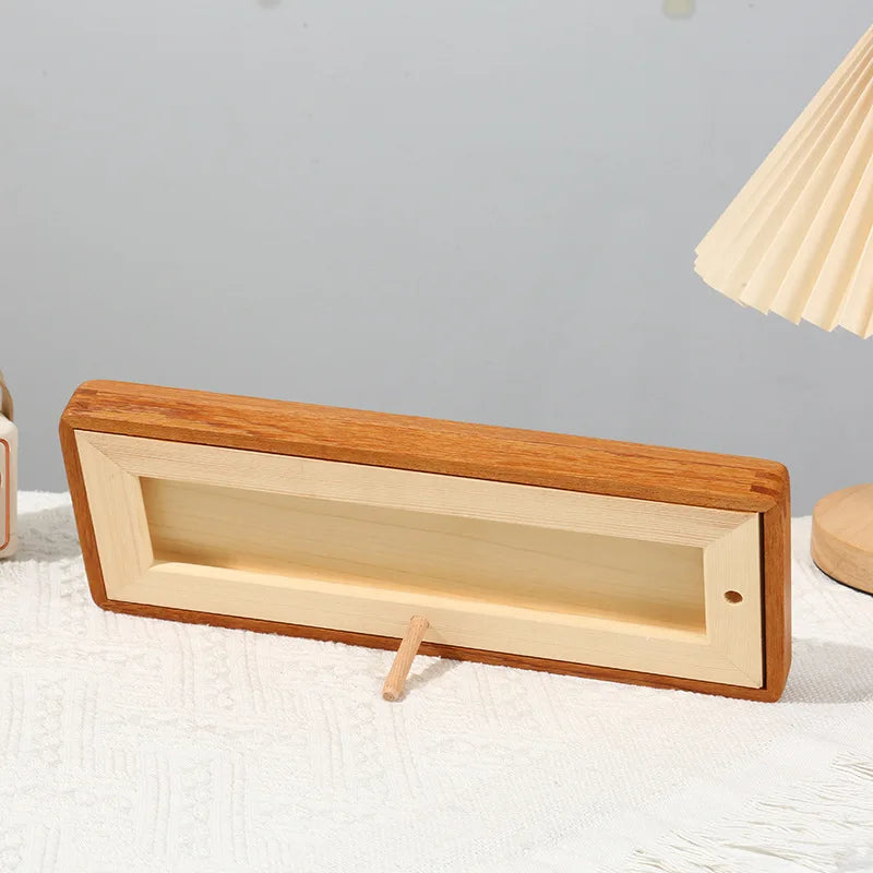 A wooden photo frame display stand with a rectangular opening and a natural wood finish is shown on a white surface.