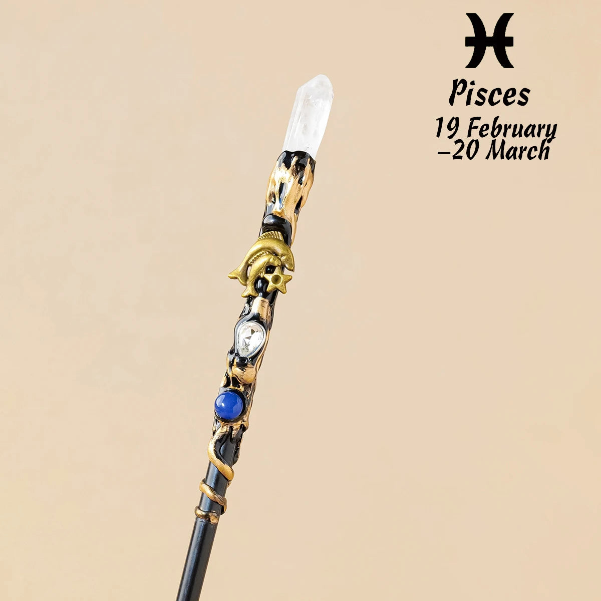 A natural clear quartz zodiac crystal wand with gold accents and a blue stone, displayed against a beige background.