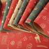 Rolls of festive red and green Christmas kraft wrapping paper featuring holiday patterns