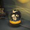 A glass crystal ball night light featuring a jellyfish silhouette and stars, casting a glow against a dark background.